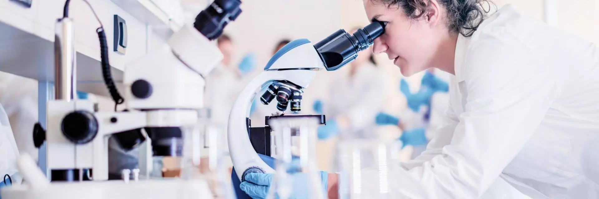 Banner image showing a scientist looking through the microscope